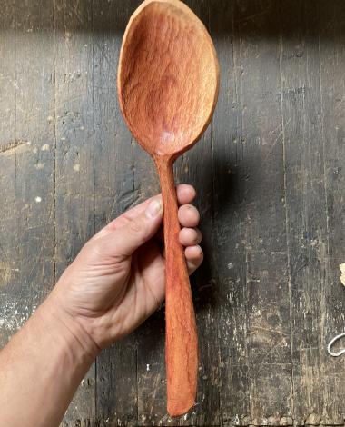 A hand holding a hand carved spoon. 
