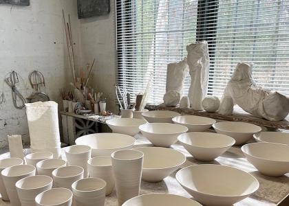ceramic mugs and bowls on a table in a studio
