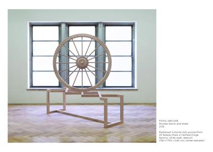 scupture of wooden spinning wheel in front of window