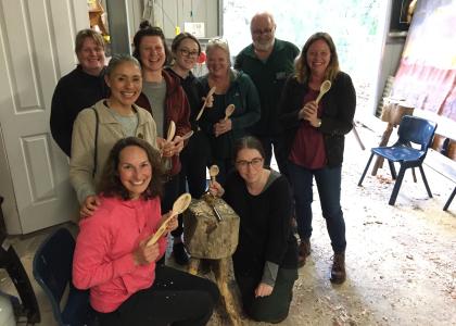Group of 8 students showing off their hand carved spoons. 