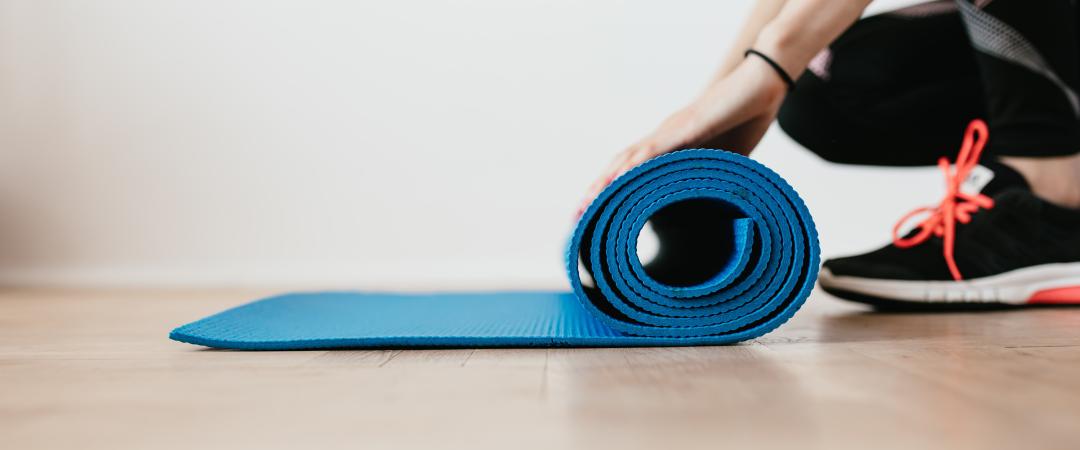 A person rolling up a Pilates mat. 